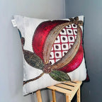 Decorative pillow with a red and gold floral design on a wooden stool against a gray wall.