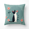 Decorative pillow with a black and white cat and pink flowers on a teal background