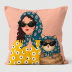 Decorative pillow with a design of a woman and a cat wearing sunglasses and headscarves on a pink background.