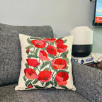 Decorative pillow with red floral pattern on a gray couch