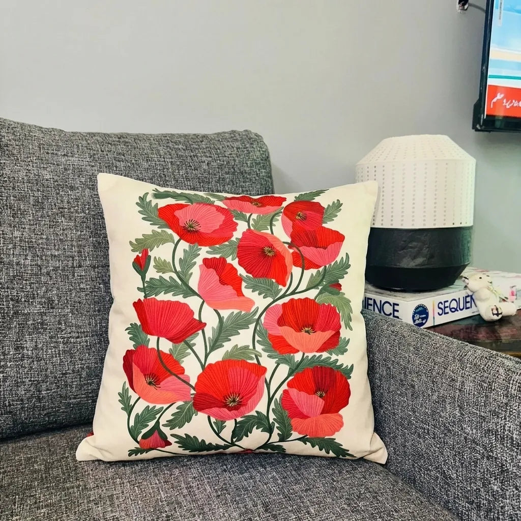 Decorative pillow with red floral pattern on a gray couch