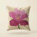 Decorative pillow with a pink flower design on a beige background